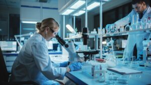 Lab worker examining samples through a microscope during testing.