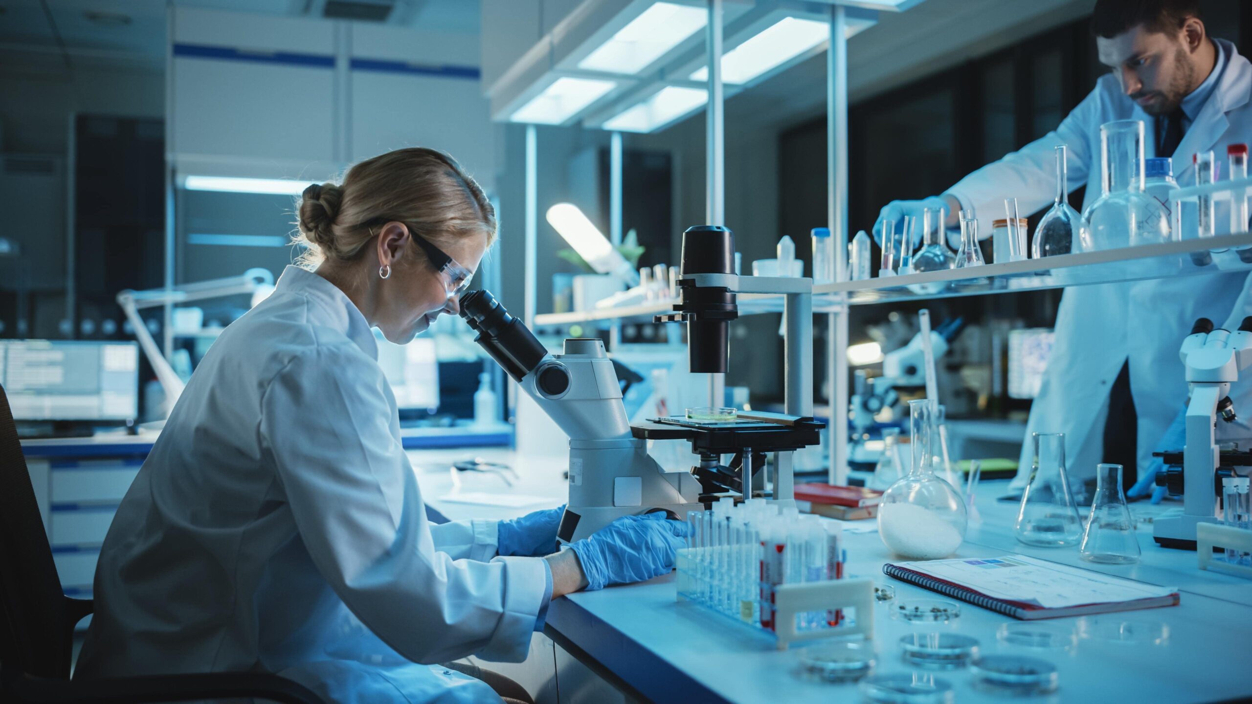 Lab worker examining samples through a microscope during testing.