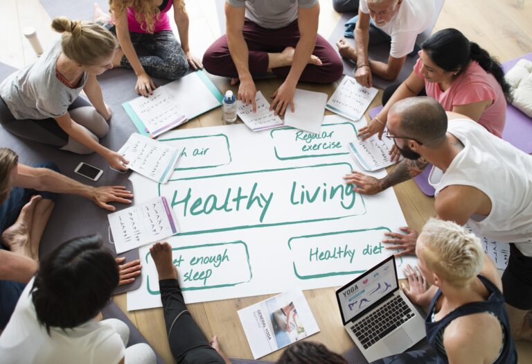 Group of people discussing healthy living with yoga charts and wellness tips, highlighting health benefits in Cyprus.
