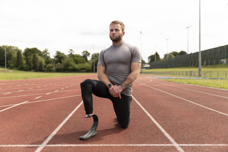 Athletic man with prosthetic leg kneeling on running track, symbolizing adaptive fitness and inclusive health in Cyprus.