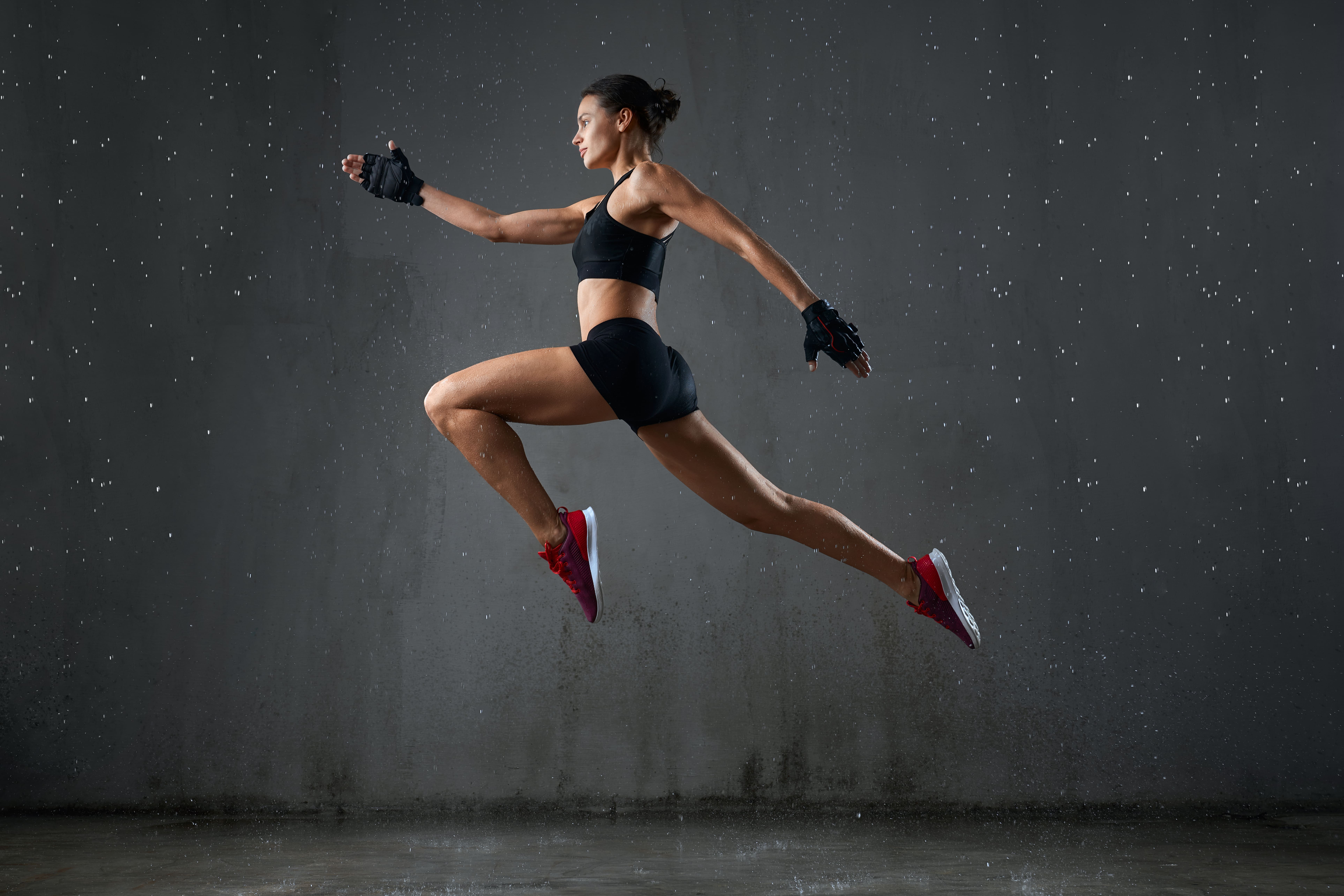 Fit woman in athletic gear leaping mid-air during an intense workout, symbolizing strength and health in Cyprus.