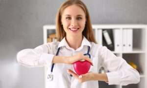 Smiling female doctor holding a red heart model at a medical laboratory in Larnaca