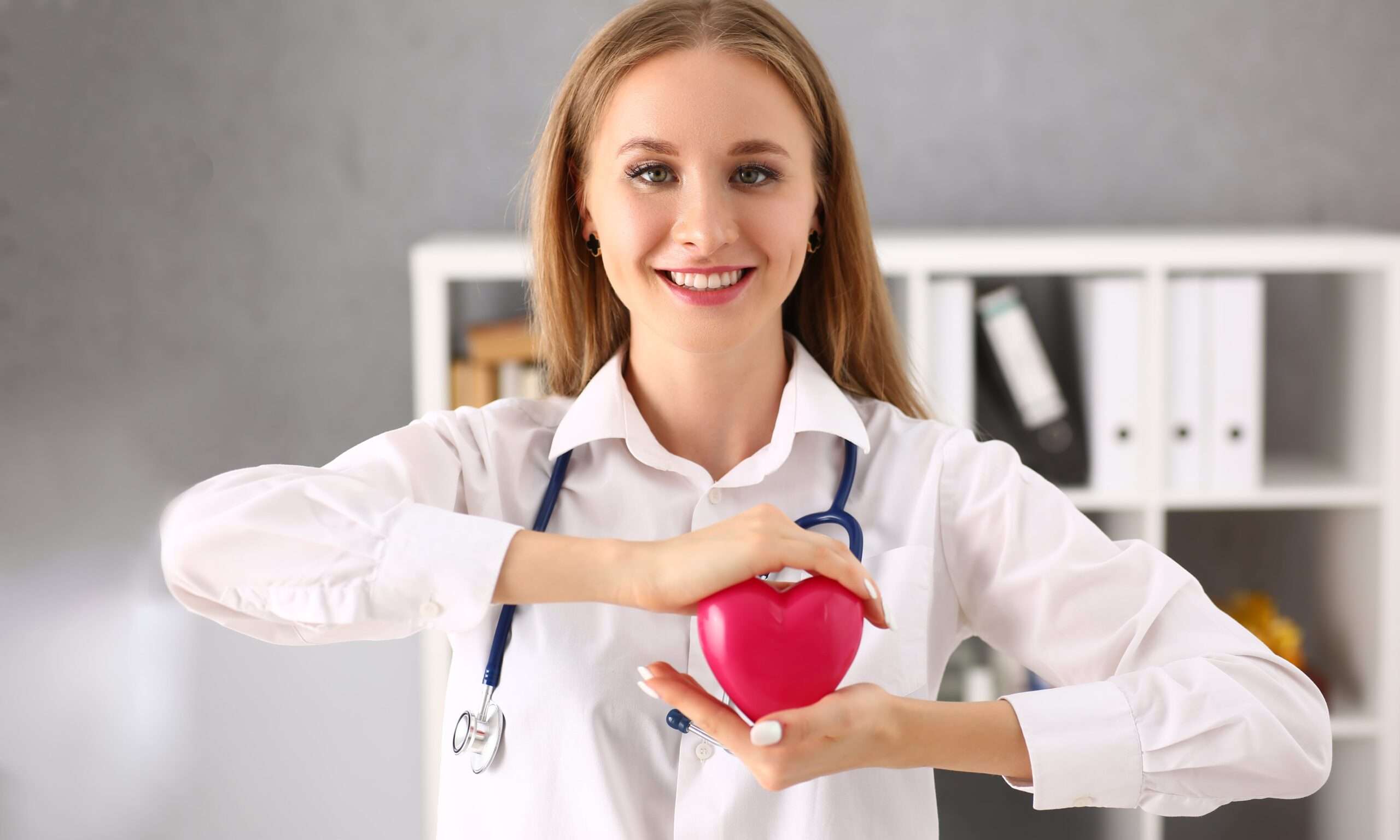 Smiling female doctor holding a red heart model at a medical laboratory in Larnaca