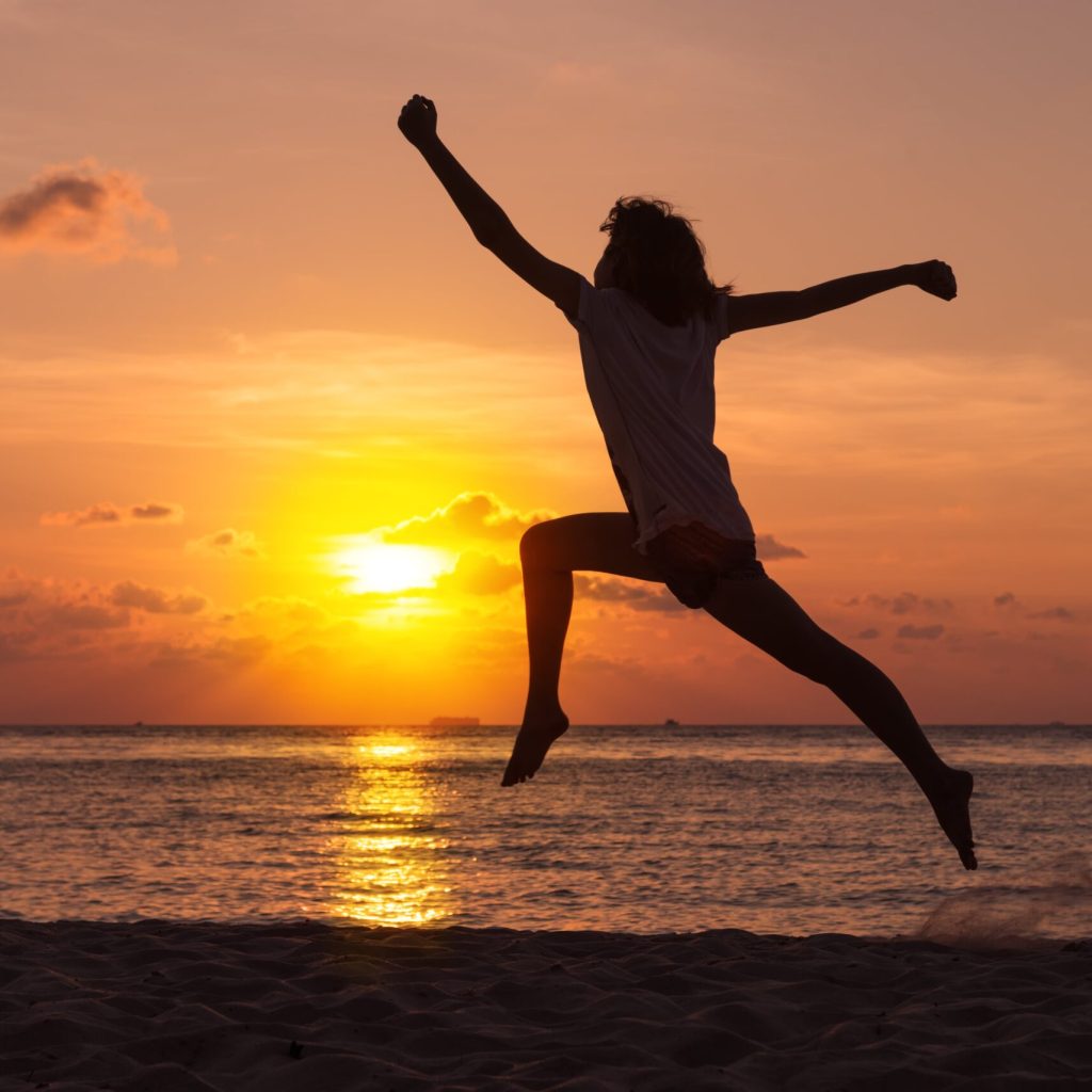 Woman Jumping on Beach at Sunset Silhouette of a woman jumping on a beach at sunset with the ocean in the background